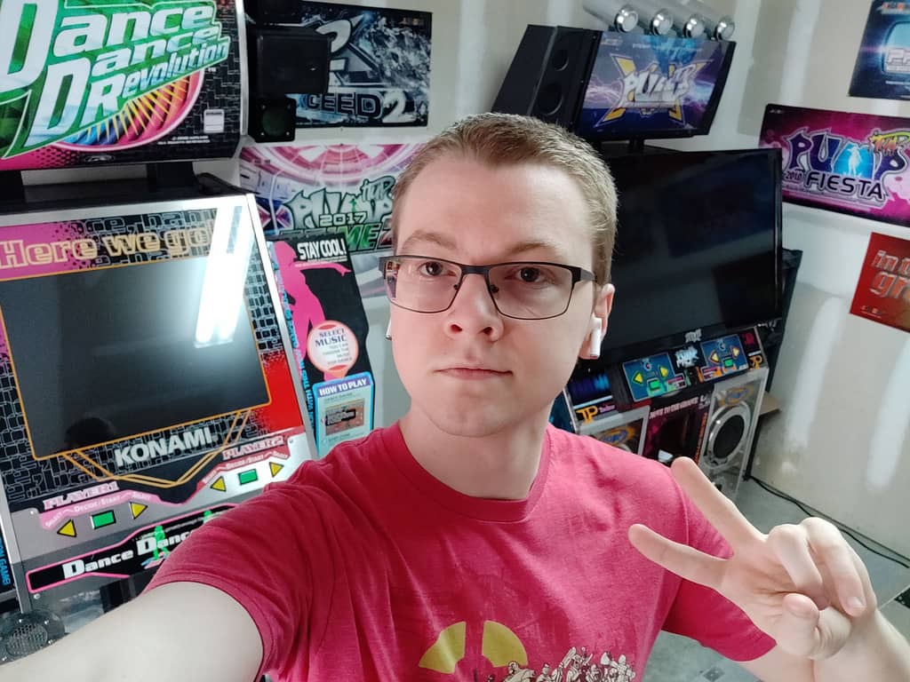 photo of clue showing a peace sign, standing in front of several arcade cabinets